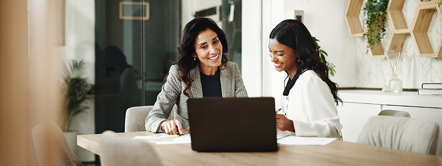 tHuman resources officer sitting at the table with new employees while looking at applications and smiling