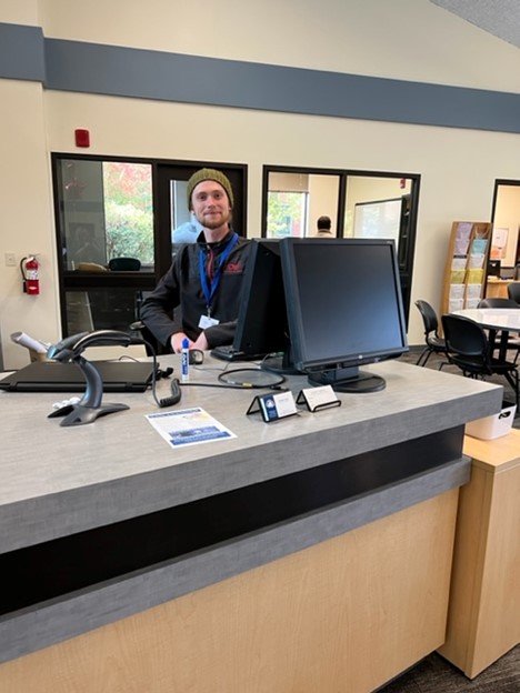 Male employee standing behind the counter at the Alan Thompson Library